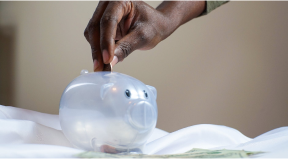 hand putting money in a penny jar